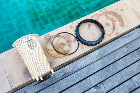 Swimming pool pump basket with lid and seal ring on swimming pool edge, pool maintenance and service conceptの写真素材
