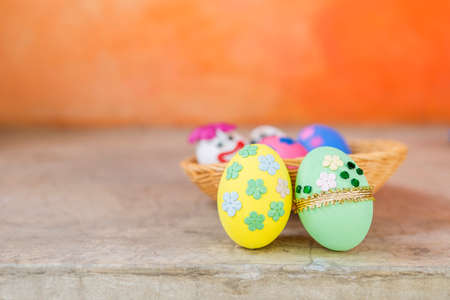 Beautiful easter egg decorate with paper flower and gold ribbon and green glass over blurred orange wall background, happy easter card background ideaの写真素材