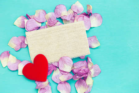 Red heart on rose flower leaves box with canvas fabric on blue background, valentine concept...