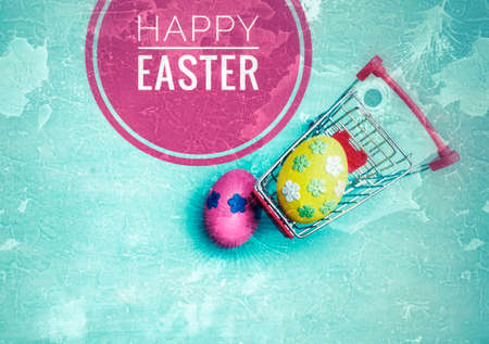 Happy easter card background idea, Yellow easter egg decorate with paper flower in shopping cart with space on blue texture backgroundの写真素材