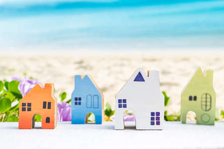 Wooden house model over blurred beach background, property and real estate business conceptの写真素材