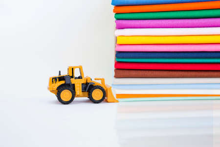 Yellow front loader truck with color cotton fabric stack on white background, textile and fashion industry, clearance saleの写真素材