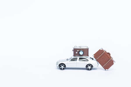 Model car with lugguage and camera toy isolate on white backgrund, travel insurance conceptの写真素材