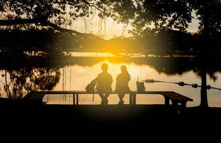 Teen friend sitting on wooden bench with lake view, friendshipの写真素材