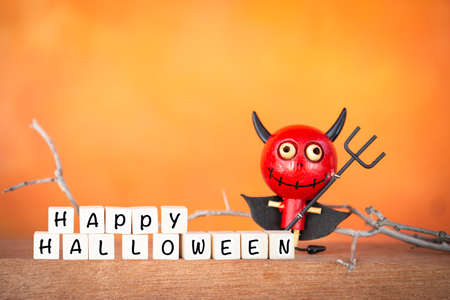 Happy Halloween with Funny red devil wooden doll over blurred orange background, Halloween...
