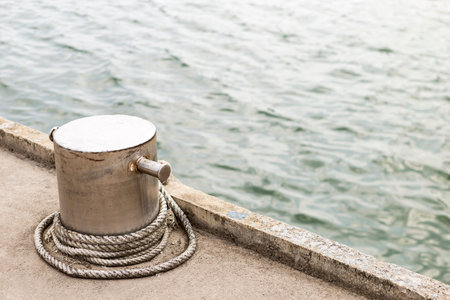 Old cross bollard with rope at harbour in south of Thailand