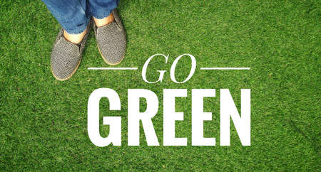 Go green banner with girl standing on green grass background, ecological conceptの写真素材