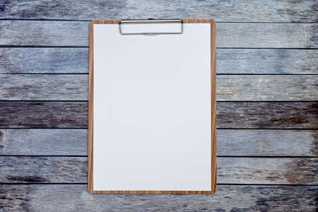 Wooden clipboard with blank white paper on wood background, stationary itemの写真素材
