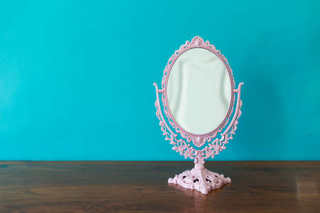 Vintage style makeup mirror on wooden table with space on blue wall background, pink vintage table mirrorの写真素材