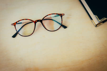 Reading glasses with old book with space on wood background, vintage tone style, business and...