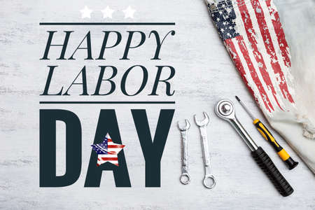 Happy Labor day sign with metal tools and jeans with USA flag print on white texture background, Labor day card concept background ideaの写真素材