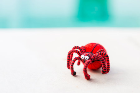 Wool red spider with black stripe over blurred background, outdoor day light, halloween decoration itemの写真素材