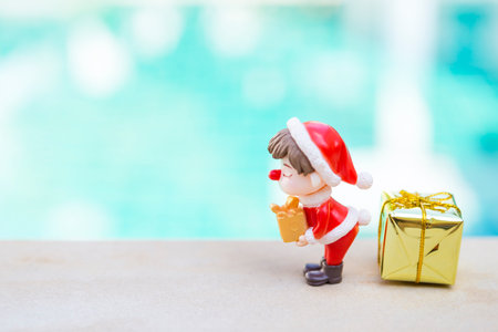 Cute little boy with Christmas costume holding gift with gold gift box over blurred blue background, Christmas giving gift concept backgroundの写真素材