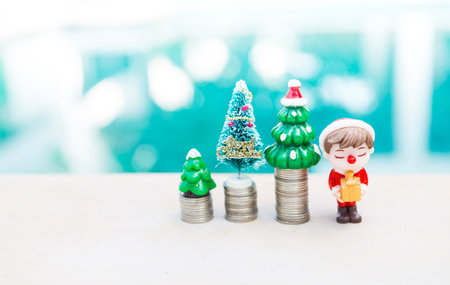 Christmas tree on coin stack with little Santa boy holding gift with space on blurred background, festive season conceptの写真素材