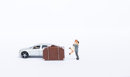 Miniature couple with toy car and luggage isolate on white background, just married, honeymoon trip, love and relationshipの写真素材