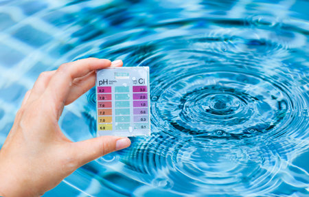 Pool tester test kit in girl hand over water background, water quality testing, quality test kit for swimming pool waterの写真素材