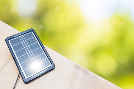 Closeup Portable solar cell panel with space on blurred natural green background, clean energy...