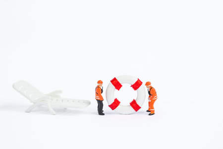 Two miniature worker in safety suite with lifebuoy and beach chair isolate on white background, safety industryの写真素材