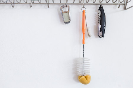 Long bottle cleaning brush and two bottle opener hanging on glass drying rack with sapce on white background, cleaning toolの写真素材
