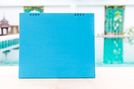 Blank blue calendar card on swimming pool edge, outdoor day lightの写真素材
