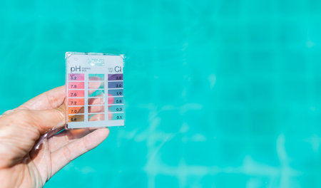 Mini water tester test kit in girl hand dipping in swimming pool water, tool for measuring pH and chlorine, high quality water tester product for safety waterの写真素材