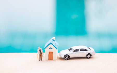 Miniature old man carry grocery bag with house and car model on swimming pool edge with space on blurred blue water, summer outdoor day light, retirement and insurance business conの写真素材
