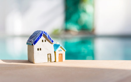 Two miniature house on swimming pool edge with morning day light, property and real estate business conceptの写真素材