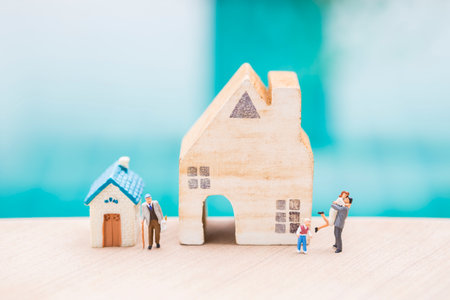 Miniature people with house model over blurred background, family house and retirment home, property businessの写真素材