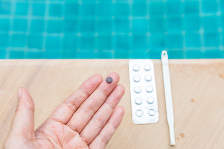 Expired tablet regents on girl hand with stirring rod and reagent tablet on swimming pool edgeの写真素材