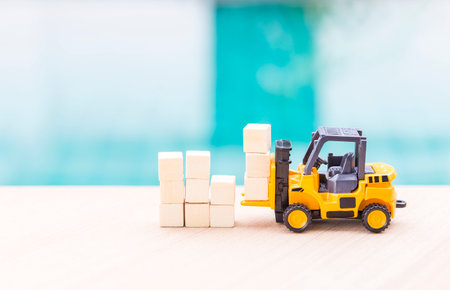 Miniature worker in safety suite on forklift truck and wooden cubes, cargo industry conceptの写真素材
