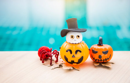 Cute wooden ghost doll wear top hat in Halloween pumpkin lantern and red yarn spider on swimming pool edge, Happy halloween concept background ideaの写真素材
