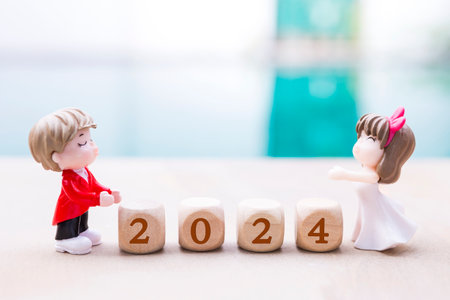 Happy New Year 2024, love and romance concept, miniature couple with wooden cube over blurred background, outdoor day lightの写真素材