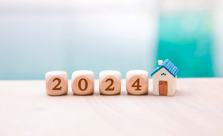 New year 2024 concept, wooden cube with number and miniature house with space on blurred background,...