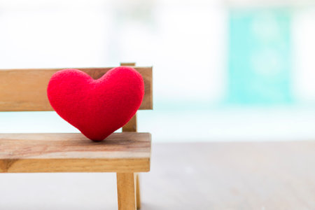 Closeup red heart on wooden chair with space on blurred background, outdoor day light, love and romance concept, simple valentine card background ideaの写真素材