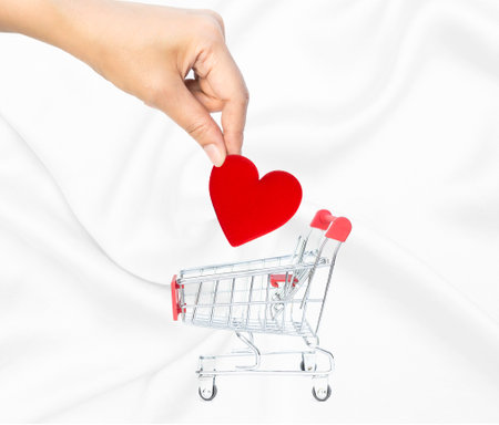 Hand holding red heart with empty shopping card on white fabric texture background, love and romance concept, valentine background idea, love marketingの写真素材