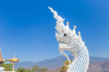 White naga head sculpture with space on clear blue sky background, White Naga sculpture at the temple on top of the mountain in northern Thailandの写真素材