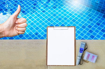Thumbs up with clipboard and water tester on swimming pool edge, swimming pool service and...