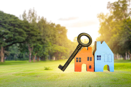 Miniature house with vintage key on green field with space on blurred forest background, property and real estate investment concept, outdoor day lightの写真素材