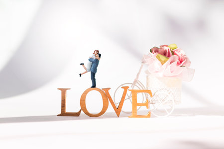 Miniature couple on love wooden font and paper flower, Valentine background idea, love and romance conceptの写真素材