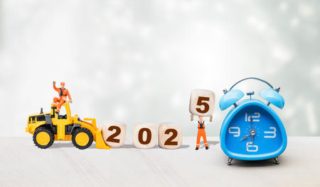 Happy New year 2025, miniature worker with wooden cube and yellow truck on white background