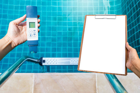 Digital swimming pool water tester in girl hand with blank report on wooden clipboard over clear swimming pool water background, quality digital water tester for pool water, servicの写真素材