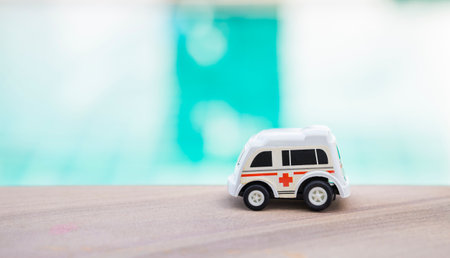 Old plastic ambulance toy car over blurred water background, outdoor day light, plastic rescue truckの写真素材
