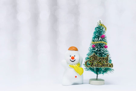 Cute little snow man with Christmas tree over blurred white bokeh background, Christmas card background ideaの写真素材