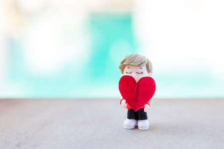 Miniature boy holding red heart with space on blurred background, outdoor day light, valentine concept background ideaの写真素材