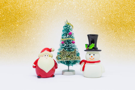 Cute little snow man and Santa Clause with Christmas tree over blurred gold glitter background, Christmas card background ideaの写真素材