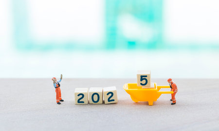 Happy New Year 2025 background idea, two miniature worker with wooden cube over blurred background