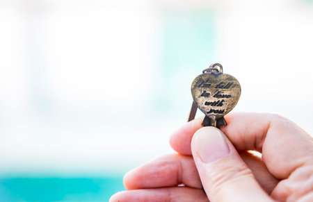 Heart shape key with message in girl hand over blurred background, love message, key to someone...