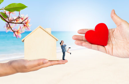 Red heart in girl hand with wooden house model in hand isolate on white background, exchange giftの写真素材