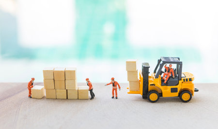 Miniature worker team with forklift truck and wooden cube over blurred background, industry conceptの写真素材