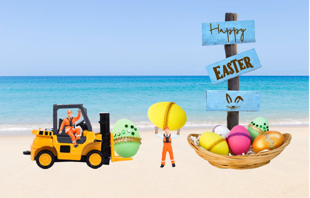 Colourful Easter egg in wooden basket with miniature worker and forklift truck  on tropical beach...